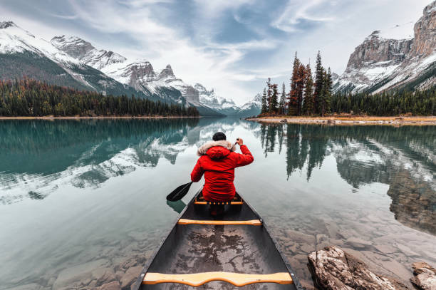 ジャスパー国立公園のマリネ湖のスピリット島で冬のコートカヌーで男性旅行者 - rocky mountains canada mountain winter ストックフォトと画像