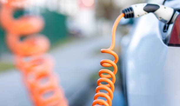 istock Spiral charging cable between charging station and electric car 1383508037