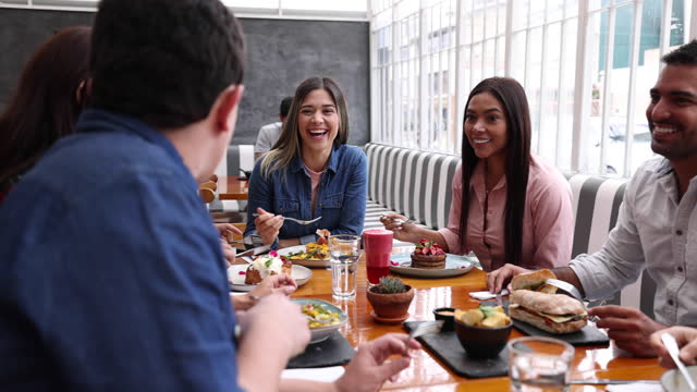 Group of friends having a great time at a restaurant while enjoying their lunch talking and laughing