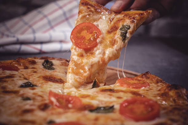 Hand holding slice of pizza
