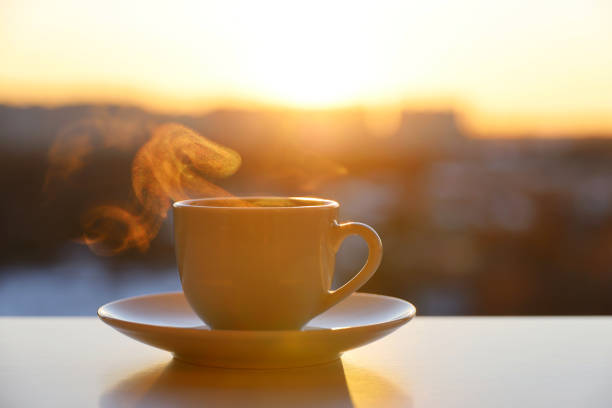 istock Hot coffee or tea cup with smoke on sunset background 1383512530