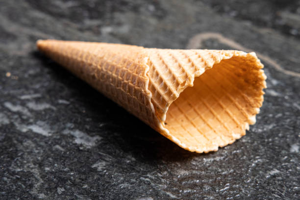 istock Empty crispy ice cream waffle cone on black lying on a black stone or table 1383512605