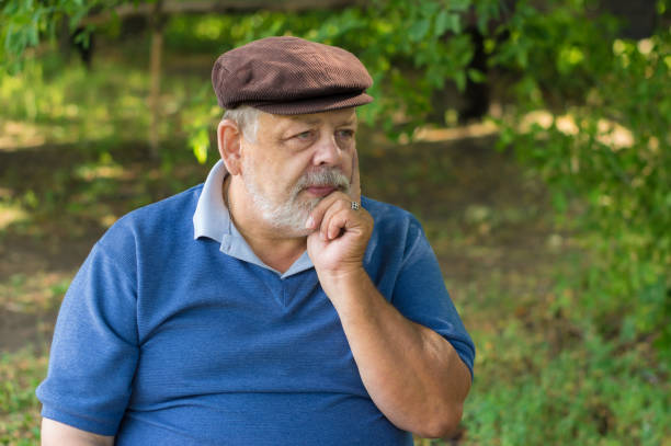 Nice outdoor portrait of Caucasian bearded senior man under tree shadow