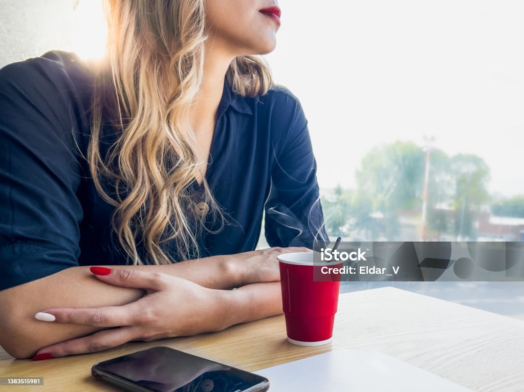 Latin woman in a black dress Latin woman in a black dress, sitting waiting for something, drinking a cup of coffee, and looking at the window. Adult Stock Photo