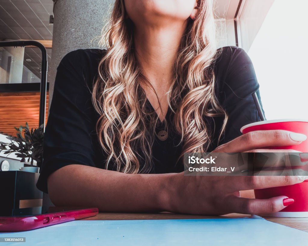 Latin woman sitting waiting, drinking a coffee Latin woman sitting waiting, drinking a coffee and with the sunlight coming through the window Adult Stock Photo