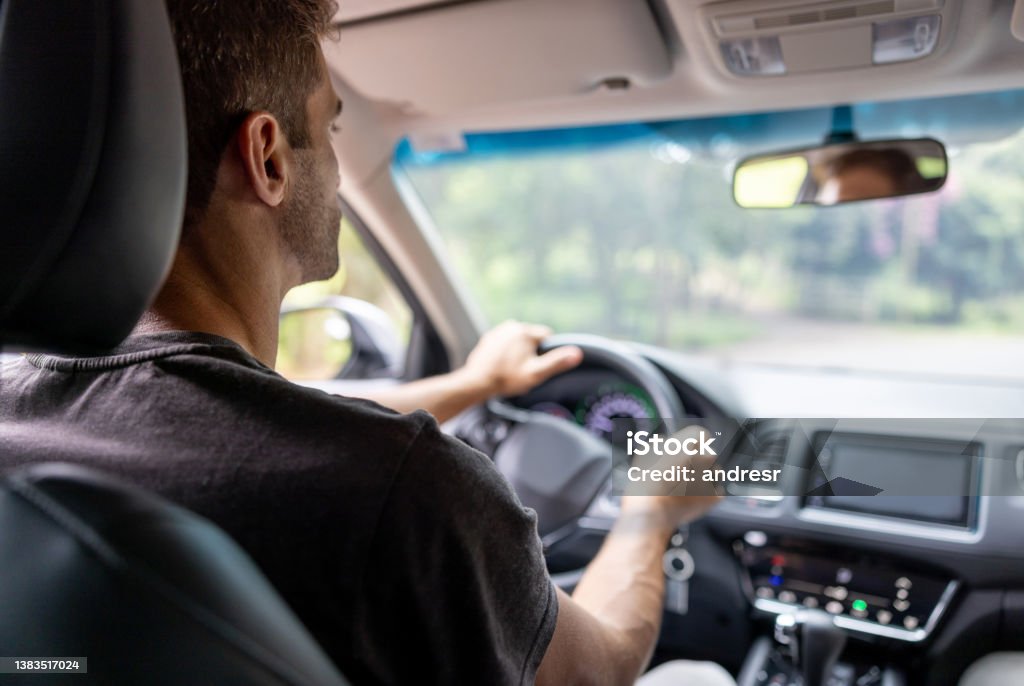 Man driving a car Casual man driving a car â POV of passenger in the back seat Crowdsourced Taxi Stock Photo