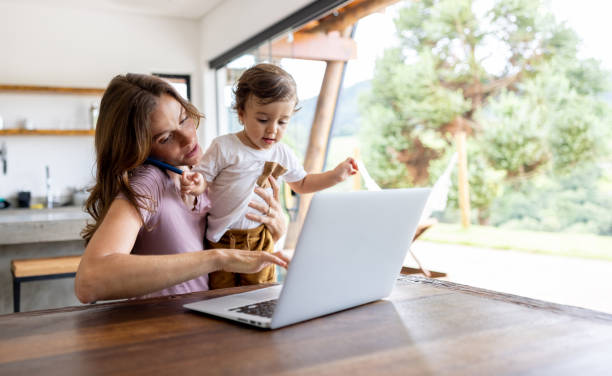Busy mother working at home while taking care of her son