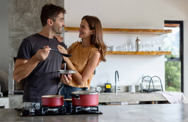 Loving couple cooking dinner together Loving Brazilian couple looking very happy cooking dinner together and smiling at each other couple isolated wife husband stock pictures, royalty-free photos & images