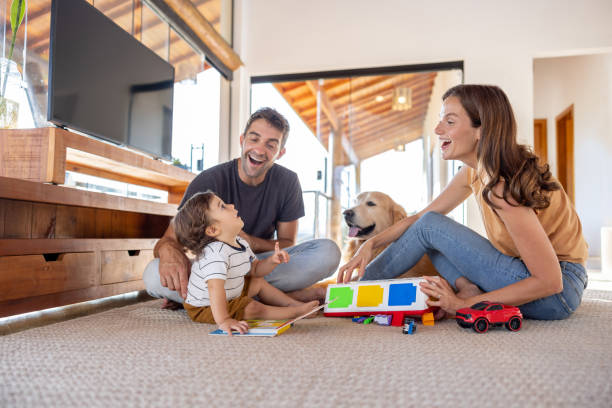 счастливые родители, играющие дома со своим малышом - family dog happiness pets стоковые фото и изображения