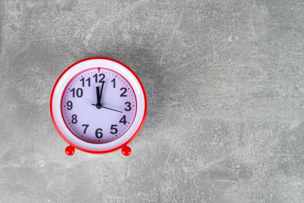 istock The red alarm clock shows the time on a gray background 1383519519