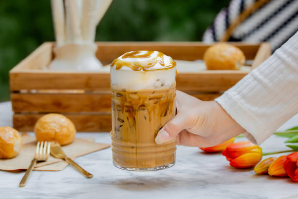 trzymająca rękę karmelowa kawa mrożona - latté cafe macchiato glass cappuccino zdjęcia i obrazy z banku zdjęć