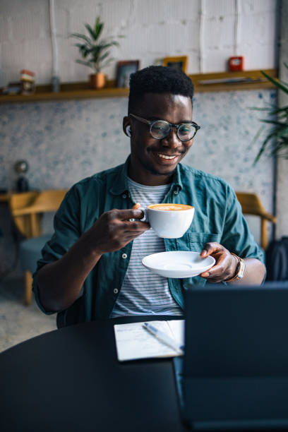 istock Happy Male Student Using his Laptop Computer for E-Learning from a Coffee Shop 1383519664