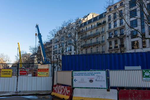 Fenced off roadworks with cranes in the background in Paris, France