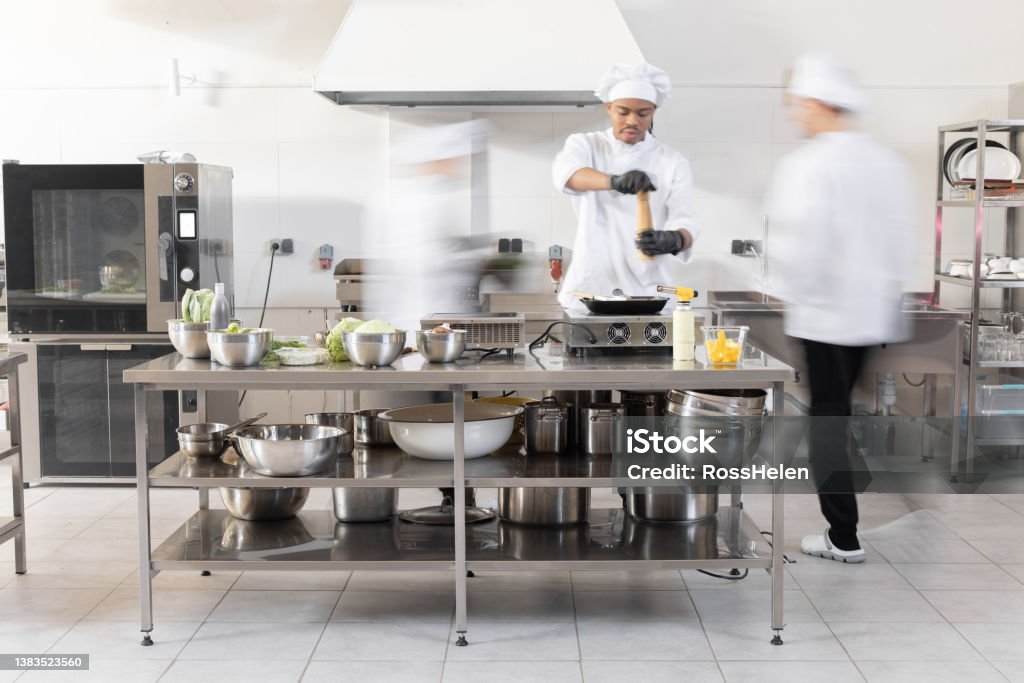 Chef cooks working in professional kitchen Chef cooks working in professional kitchen. Chefs hurry up, actively cooking meals for restaurant. Long exposure with motion blurred figures Blurred Motion Stock Photo