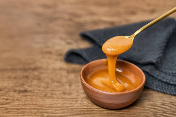 Manuka honey dipper dipping in raw organic liquid from Manuka flowers in New Zealand .Bees harvesting exclusively from this healthy antibacterial antifungal property flower stock photo