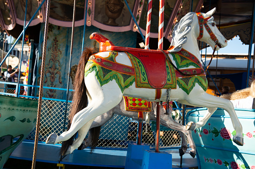 Pretty kid on carousel horse. Cute girl is riding attraction. Fun celebration