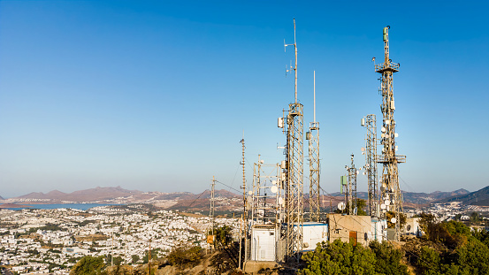 View of Telecommunication mast TV antennas at sunrise on mountain with city on background. Antenna Telephone Network Communication