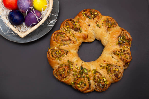 istock Easter roll with nuts and colored eggs in heart shaped basket. Brown background.. 1383525671