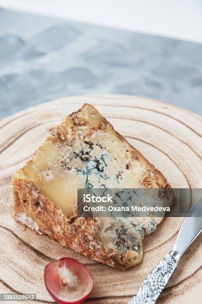 Large Piece Of Stilton Cheese Is Lying On A Wooden Board Delicacy Cheese With Blue Mold Stilton With Grapes Stock Photo - Download Image Now