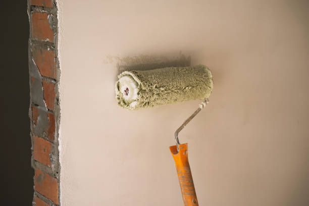 istock roller with a yellow handle in the process of applying paint to a brick wall 1383530281