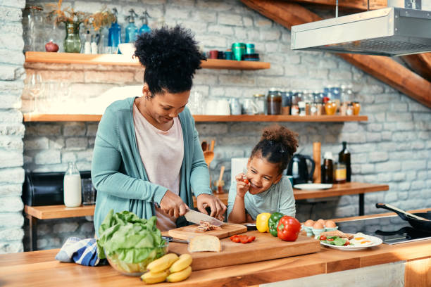istock Happy black  mother and daughter having fun while preparing food in the kitchen. 1383532251