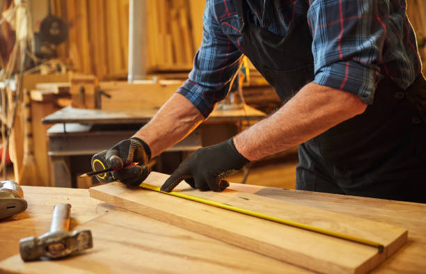 istock Carpenter working with a wood, marking plank with a pencil and taking measurements to cut a piece of wood to make a piece of furniture in a carpentry workshop, close-up view 1383532550