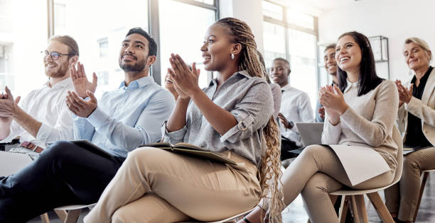 aufnahme einer gruppe von geschäftsleuten, die während einer konferenz in die hände klatschen - training business seminar clapping stock-fotos und bilder