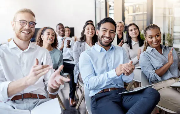 Photo of Shot of a group of businesspeople clapping hands during a conference