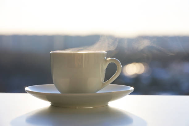 istock Hot coffee or tea cup with steam smoke on shining sun background 1383534116