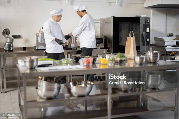 Two Chef Cooks Standing Together In Professional Kitchen Stock Photo - Download Image Now