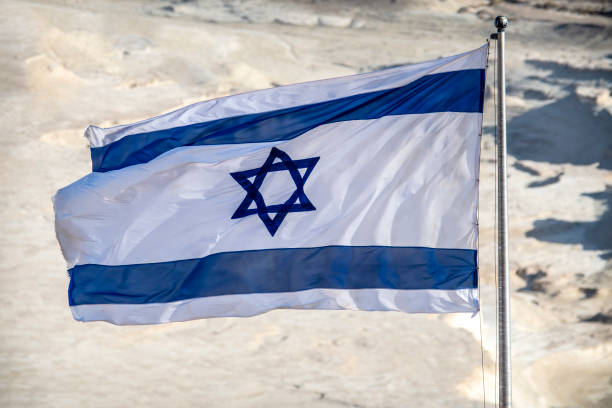 istock Israel flag flying above desert backdrop in sunshine 1383536696