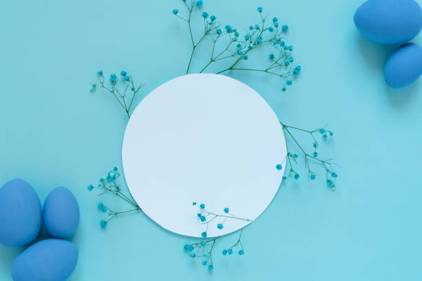 istock Easter composition with eggs and twigs of blue flowers around white circle frame 1383537525