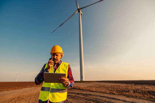 istock Engineer standing in front of turbines on a wind farm 1383538380