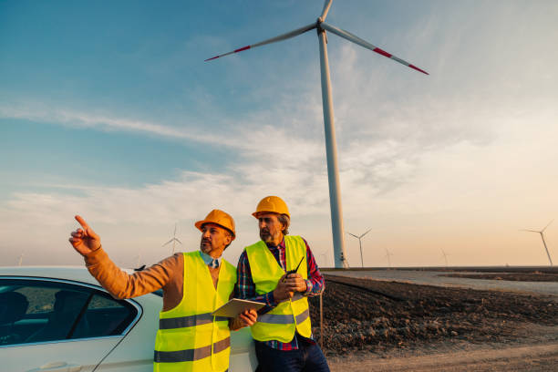 istock Workers looking and checking wind turbines at field 1383538406