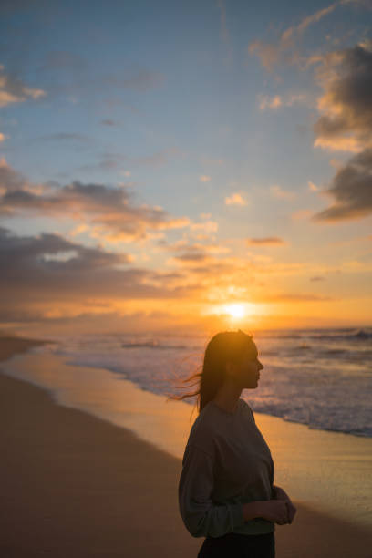 istock Young woman walks down sandy beach at sunrise 1383541183