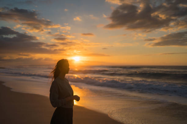 istock Young woman walks down sandy beach at sunrise 1383541184
