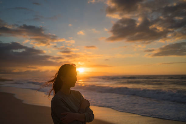 istock Young woman walks down sandy beach at sunrise 1383541283