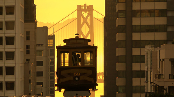 Cable car on the hills of San Francisco with Bay Bridge in the background
