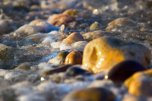 istock Sea rolling and receding water in rays of setting sun. 1383547951