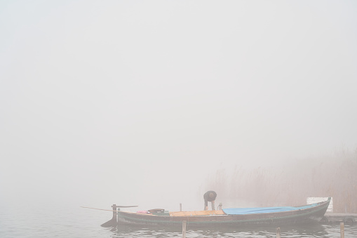 Fisherman setting boat in wooden dock on cold foggy winter morning