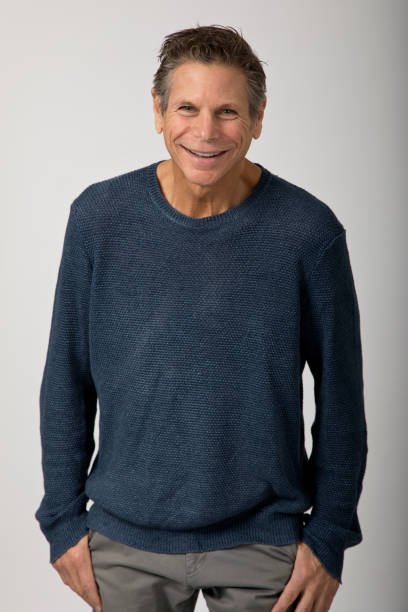 istock Man in sweater thumbs in pockets smiling at camera 1383549282