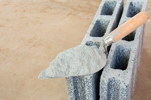 Cement powder or mortar with  trowel put on the Concrete brick for construction work.