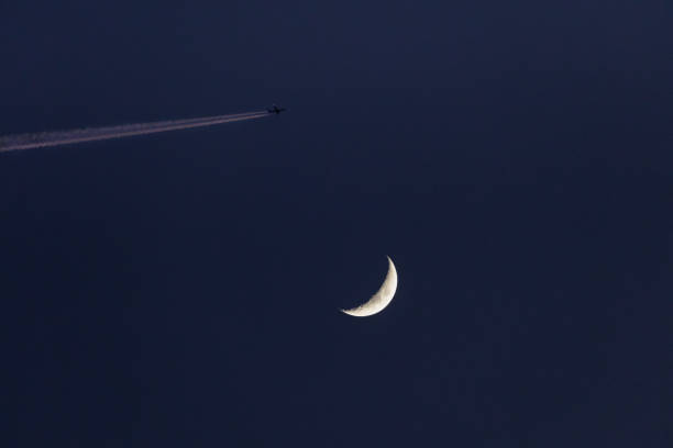 Airplane passing by waxing Moon on blue sky Closeup of the waxing moon and an airplane passing close by, leaving a contrail which is illuminated by the setting sun - - early evening capture against dark blue sky. Stuttgart, Germany February 5, 2022 contrail moon on a night sky stock pictures, royalty-free photos & images