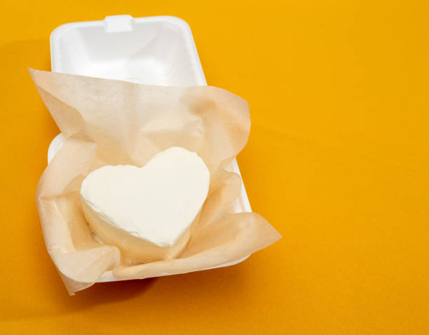 Bento cake in the form of heart in eco-friendly packaging on yellow background. Trending dessert. Image for food websites. Selective focus. stock photo