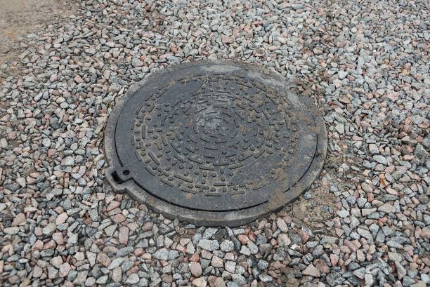 istock one round black metal sewer manhole among gray fine rubble 1383556580