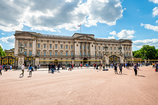 London, Uk - 26 March 2022: Front facade of Buckingham Palace, with the Victoria Memorial and the Memorial Gardens on a spring day. The union Jack indicates the Queen Elizabeth II is in residence.