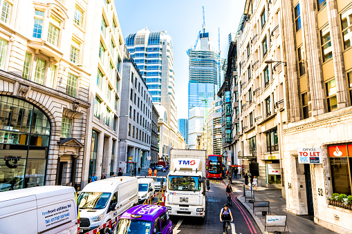 London, UK - June 22, 2018: Red double-decker bus on street alley wide angle view with business city of London district with construction skyscraper modern buildings