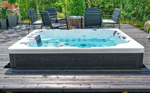 Large hot tub embedded in the backyard terrace Large hot tub embedded in the backyard terrace. A sunny summer's day in the shelter of a green garden. Everyday luxury and relaxation in your own backyard. Spa complex, vacation and traveling concept. hot tub stock pictures, royalty-free photos & images