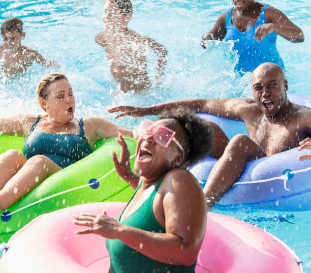 amis et famille multiraciaux éclaboussant sur une rivière paresseuse - floating on water swimming pool men water photos et images de collection