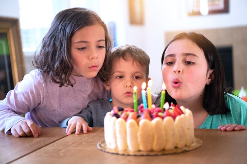 Children celebrating birthday blowing a birthday cake candles
